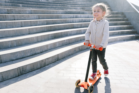 Kid riding a scooter in the cityの写真素材