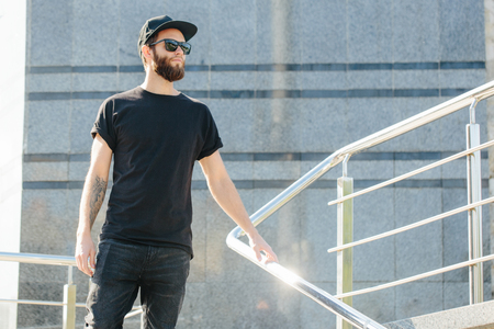Hipster handsome male model with beard  wearing black blank  t-shirt with space for your logo or design in casual urban styleの写真素材