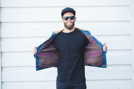 Hipster man having fun smiling and  wearing black jeans, t-shirt and a baseball capの写真素材