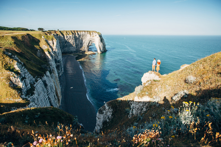 Couple looking at Etretat cliffs along the ocean shore in Franceの写真素材