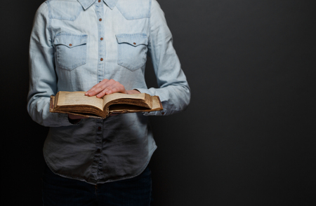 Woman reading an old Bible over a gray backgroundの写真素材