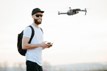 Man flying a drone in the city using a controllerの写真素材