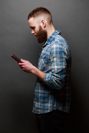 Handsome man reading and praying over Bible in a dark room over gray textureの写真素材