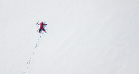 Child girl playing and making a snow angel in the snow. Top flat overhead viewの写真素材