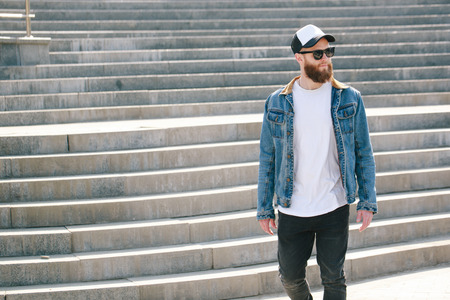 Hipster man walking wearing black jeans, t-shirt and a baseball capの写真素材