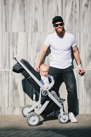 Father walking with a stroller and a baby in the city streetsの写真素材