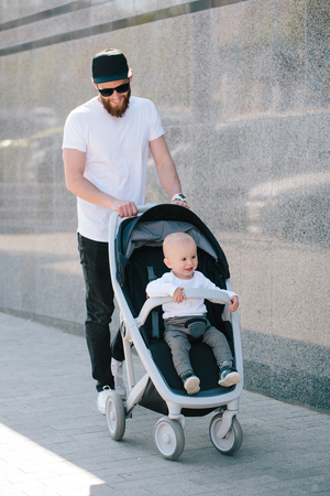 Father walking with a stroller and a baby in the city streetsの写真素材