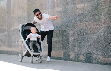 Father walking with a stroller and a baby in the city streets