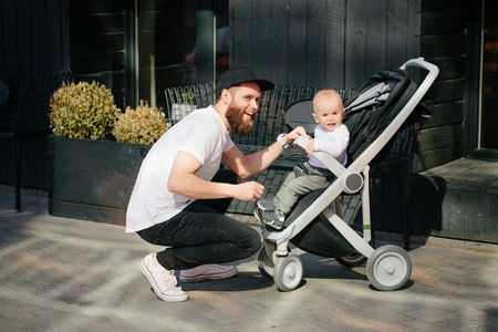 Father walking with a stroller and a baby in the city streetsの写真素材