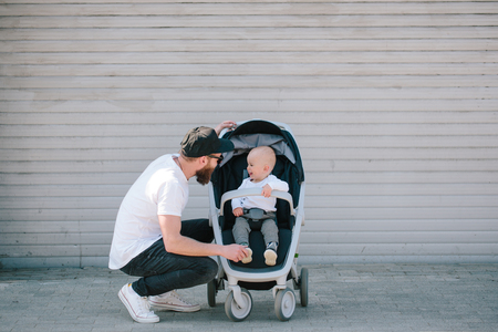 Father walking with a stroller and a baby in the city streetsの写真素材