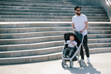 Father walking with a stroller and a baby in the city streetsの写真素材