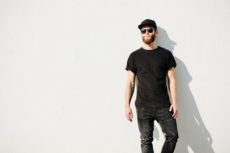 Hipster handsome male model with beard wearing black blank t-shirt with space for your logo or design in casual urban styleの写真素材