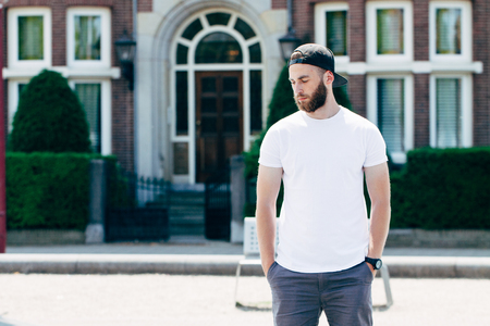 Hipster handsome male model with beard wearing white blank t-shirt with space for your logo or design in casual urban styleの写真素材