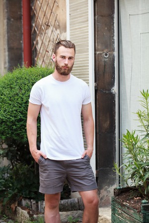 Hipster handsome male model with beard wearing white blank t-shirt with space for your logo or design in casual urban styleの写真素材