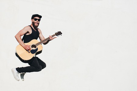Guitar player singing outside. Hipster guitar player with beard and black clothesの写真素材