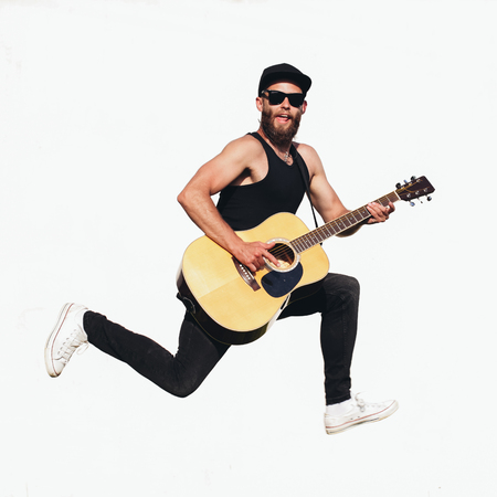 Guitar player singing outside. Hipster guitar player with beard and black clothesの写真素材