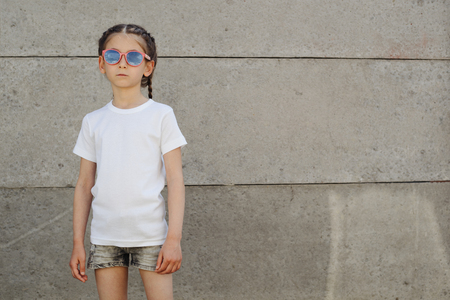 Kid girl wearing white t-shirt with space for your logo or design in casual urban styleの写真素材