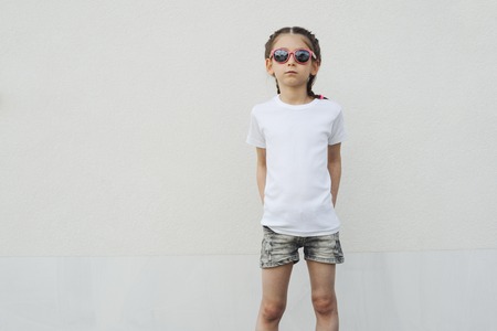 Kid girl wearing white t-shirt with space for your logo or design in casual urban styleの写真素材