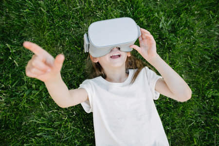 Kid girl using virtual reality glasses outsideの写真素材