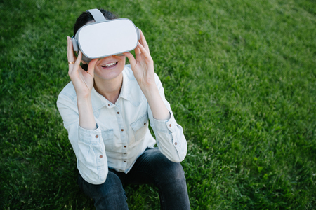 Woman using virtual reality glasses outside on a green grassの写真素材