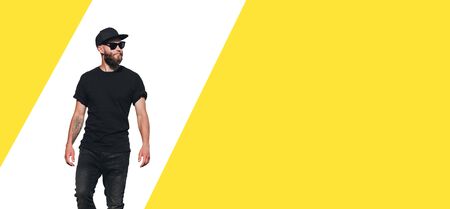 Hipster handsome male model with beard wearing black blank t-shirt with space for your logo or design in casual urban styleの写真素材