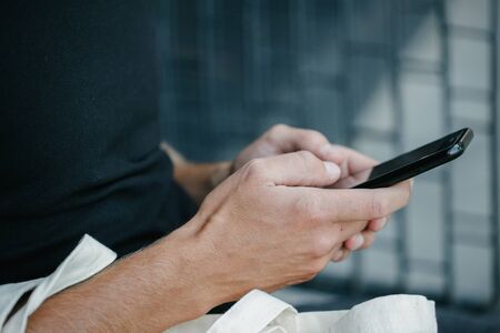 Man holding a phone over dark backgroundの写真素材