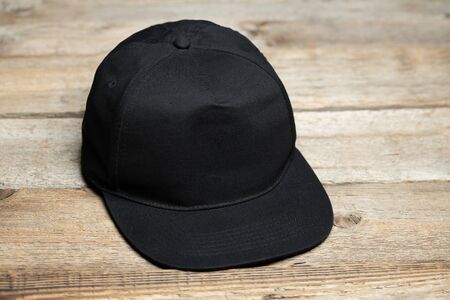Black baseball cap for mock up or your logo over wooden backgroundの写真素材