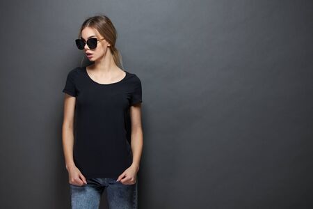 Sexy woman or girl wearing black blank t-shirt with space for your  mock up or design in casual urban style over gray backgroundの写真素材