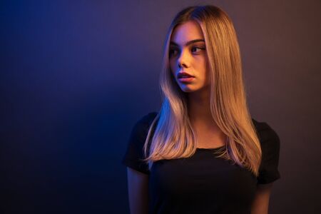 Sexy young blonde girl portrait over gray paper background in neon lightsの写真素材