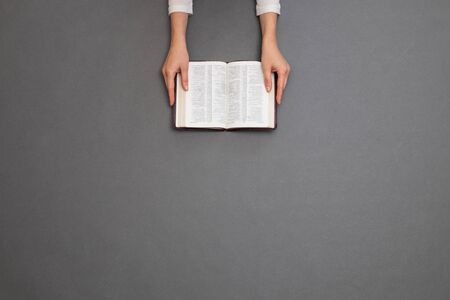 Woman reading a bible over gray table. Overhead imageの写真素材