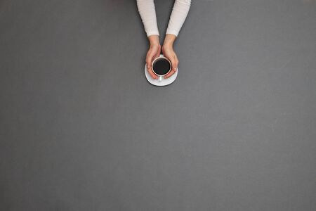 Woman hands holding a coffee cup. Overhead imageの写真素材