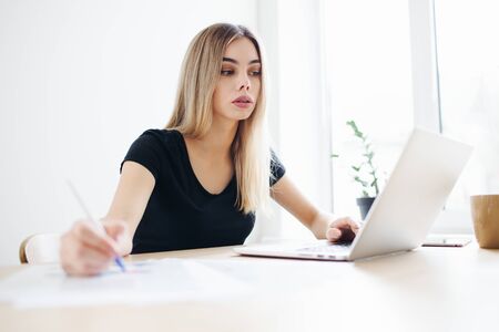 Pretty business freelancer woman working on her computer. Girl at her workspace. Start-up office backgroundの写真素材