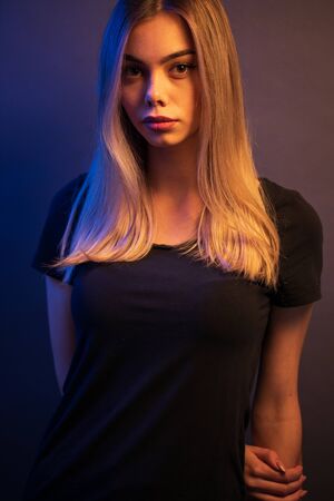 Sexy young blonde girl portrait over gray paper background in neon lightsの写真素材