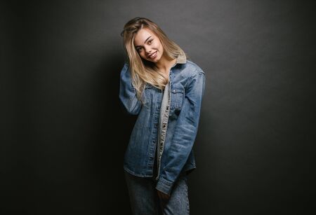 Fashion portrait of a sexy blonde woman with a make up wearing jeans clothes over gray backgroundの写真素材