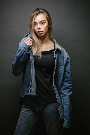 Fashion portrait of a sexy blonde woman with a make up wearing jeans clothes over gray backgroundの写真素材