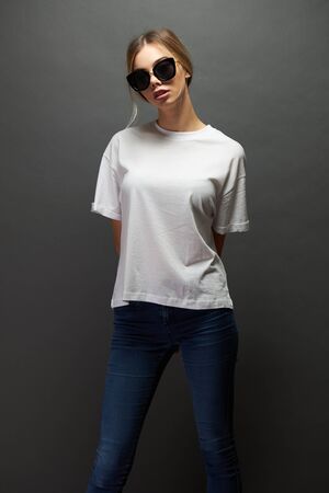 Sexy woman or girl wearing white blank t-shirt with space for your logo, mock up or design over gray backgroundの写真素材