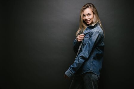 Fashion portrait of a sexy blonde woman with a make up wearing jeans clothes over gray backgroundの写真素材