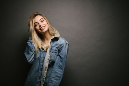 Fashion portrait of a sexy blonde woman with a make up wearing jeans clothes over gray backgroundの写真素材