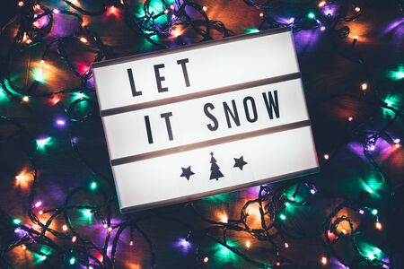 Let it snow sign in lightbox over christmas garland lights in the darkの写真素材