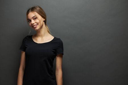 Sexy woman or girl wearing black blank t-shirt with space for your logo, mock up or design in casual urban style over gray backgroundの写真素材