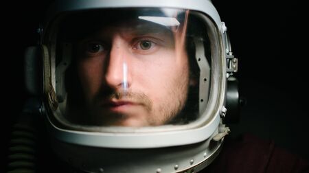 Astrounaut man in a helmet looking ahead exploring the earth in a darkの写真素材