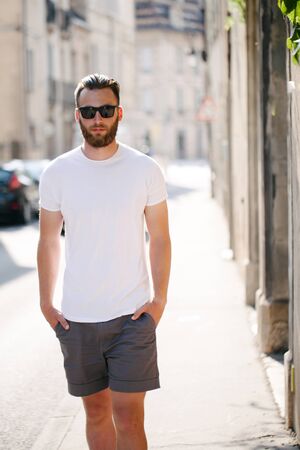 Hipster handsome male model with beard wearing white blank t-shirt  with space for your logo or design in casual urban styleの写真素材