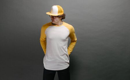 Man model with beard wearing white and yellow blank Long Sleeve Shirt for mock up and a baseball cap with space for your logo or design over gray backgroundの写真素材