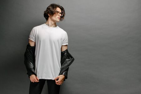 Hipster handsome male model with glasses wearing white blank t-shirt and black jeans with space for your logo or design in casual urban styleの写真素材