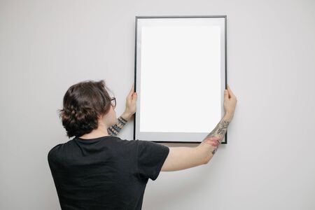 Man holding a picture frame or poster for mock up wearing black clothesの写真素材
