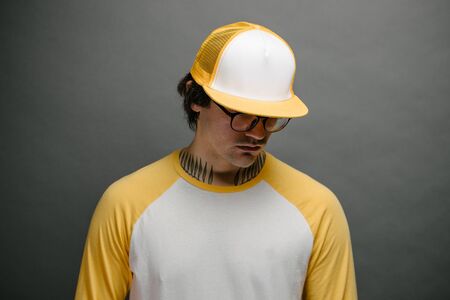 Hipster handsome male model wearing yellow blank baseball cap with space for your logo over gray backgroundの写真素材