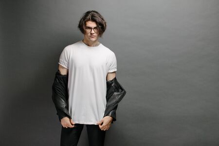 Hipster handsome male model with glasses wearing white blank t-shirt and black jeans with space for your logo or design in casual urban styleの写真素材