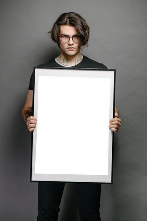Man holding a picture frame or poster for mock up wearing black clothesの写真素材