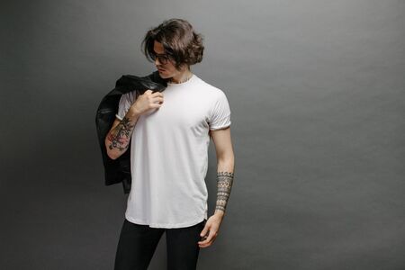Hipster handsome male model with glasses wearing white blank t-shirt and black jeans with space for your logo or design in casual urban styleの写真素材