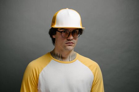 Hipster handsome male model wearing yellow blank baseball cap with space for your logo over gray backgroundの写真素材